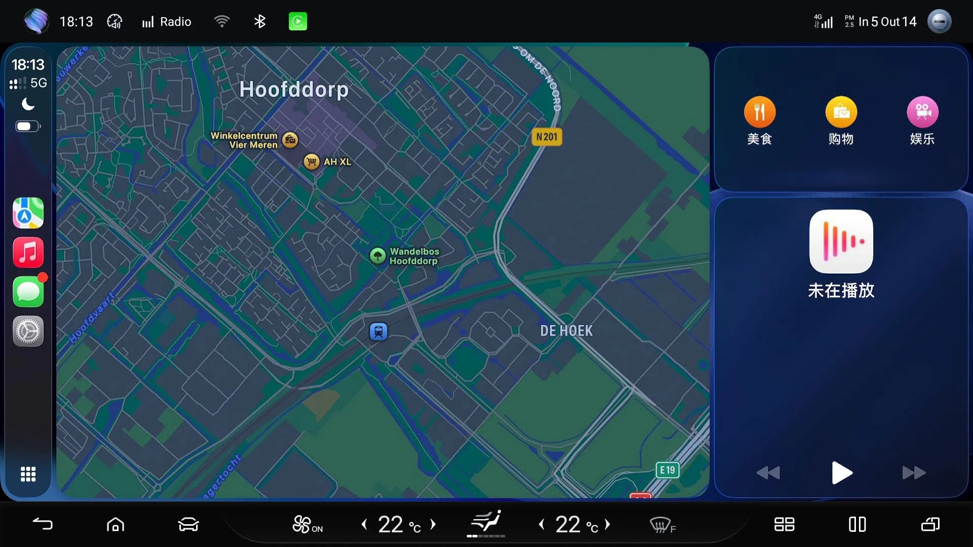 Apple CarPlay on the head unit: the CarPlay sidebar with Maps, Music, Messages and Settings, a map of Hoofddorp filling the main area, and category shortcuts plus a media widget on the right; the vehicle’s own climate bar runs along the bottom.