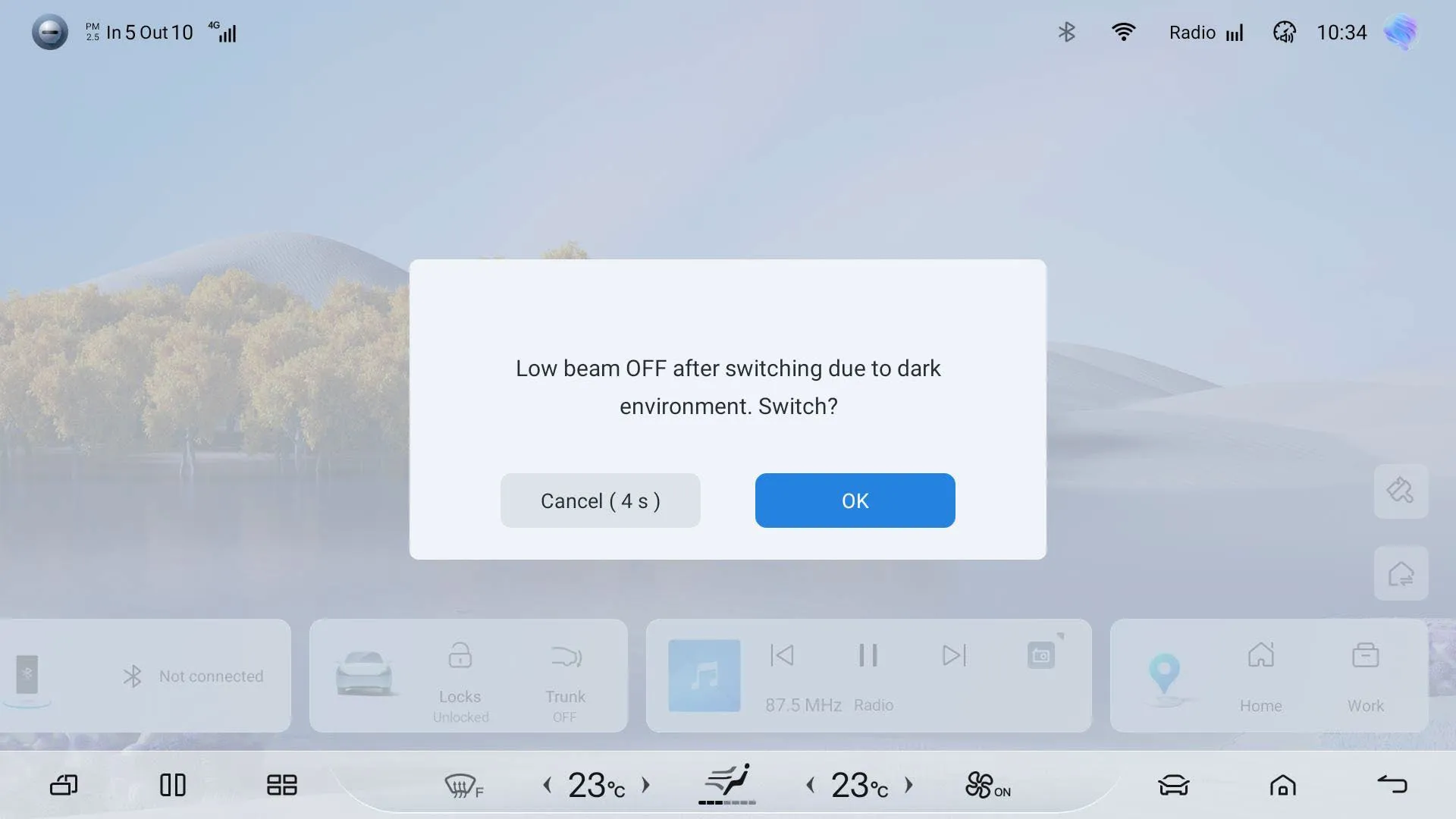 Head-unit screenshot of a dialog over the dimmed home screen reading ‘Low beam OFF after switching due to dark environment. Switch?’ with buttons ‘Cancel (4 s)’ and ‘OK’.