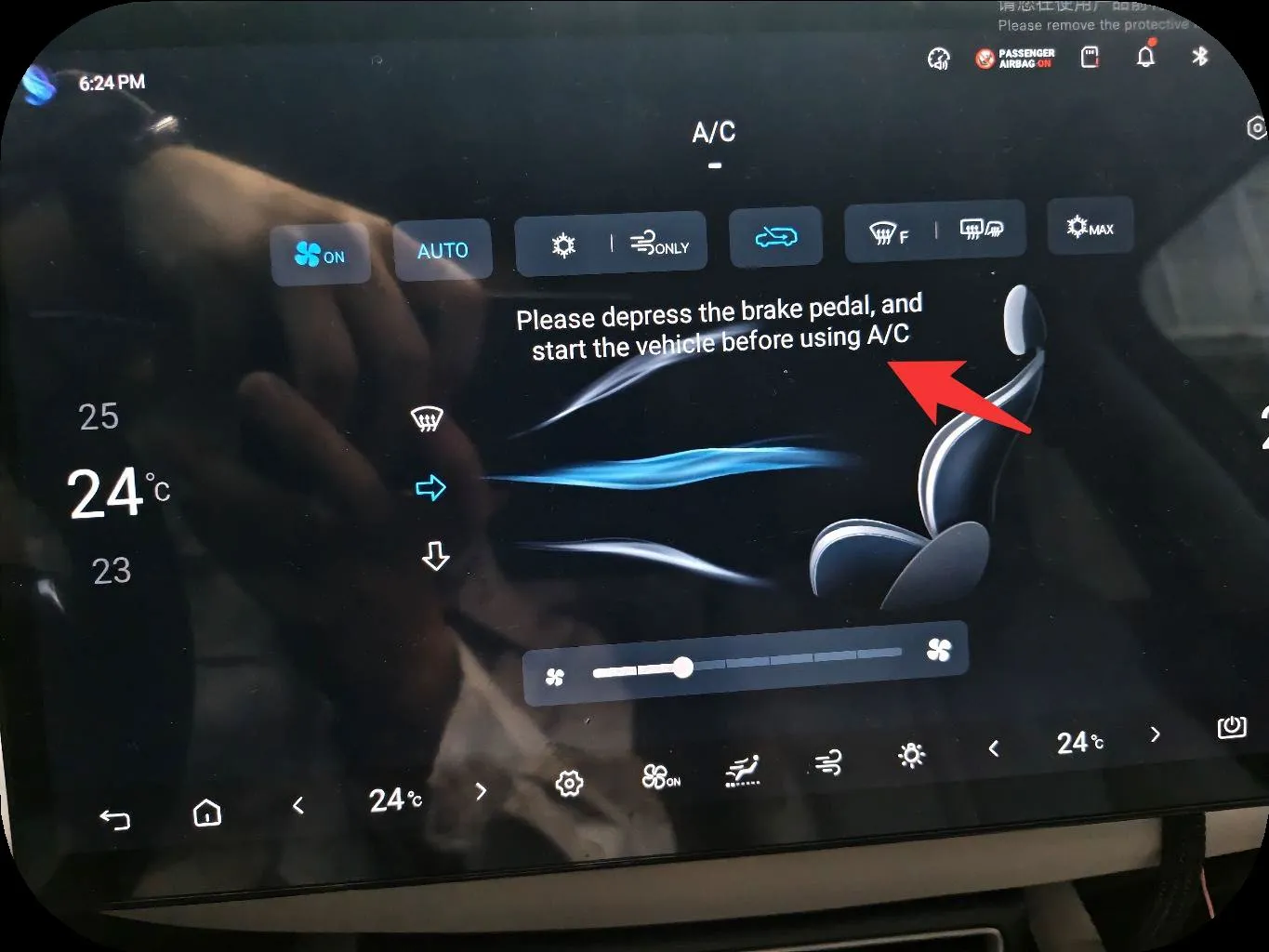 Photo of the head-unit A/C screen with fan, AUTO, recirculation and defrost buttons; a red arrow points to the on-screen message ‘Please depress the brake pedal, and start the vehicle before using A/C’.